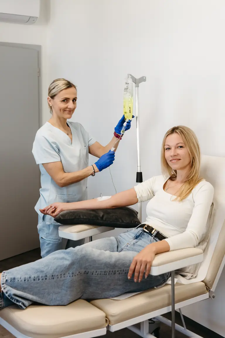 Sestra napojuje pacientce infuzi v křesle infuzního centra